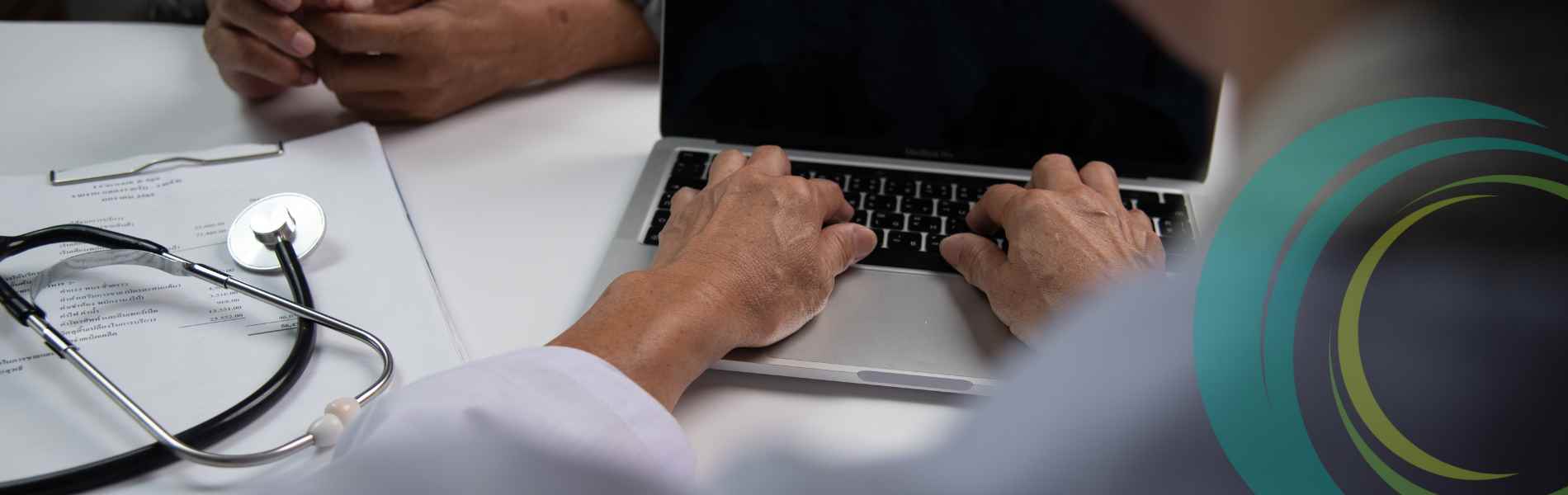 Stethescope next to doctor typing on laptop