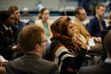 A person in a headscarf sitting in a room</p>
<p>Description automatically generated